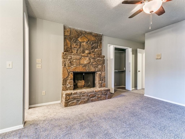 unfurnished living room featuring ceiling fan, carpet floors, a textured ceiling, and a fireplace