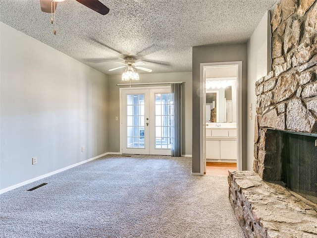 interior space with french doors, a textured ceiling, ceiling fan, light colored carpet, and a fireplace