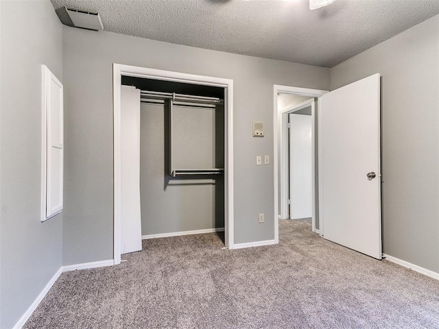 unfurnished bedroom featuring light carpet, a textured ceiling, and a closet