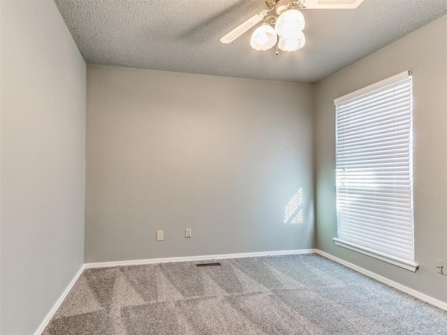 carpeted empty room with ceiling fan, a textured ceiling, and a wealth of natural light