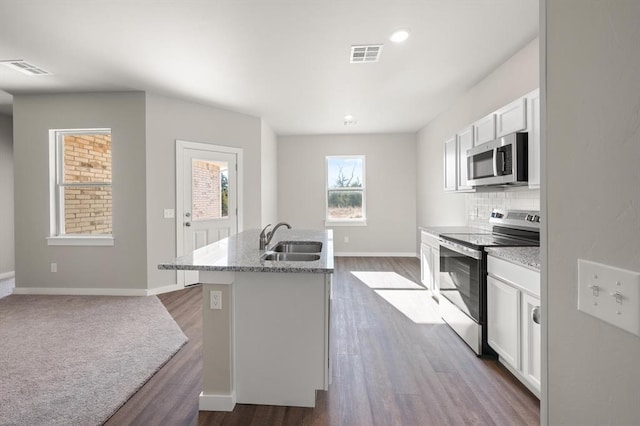 kitchen with dark wood-type flooring, sink, an island with sink, stainless steel appliances, and white cabinets