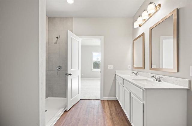 bathroom featuring vanity, wood-type flooring, and tiled shower