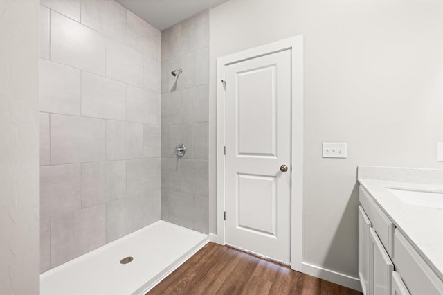 bathroom featuring a tile shower, hardwood / wood-style floors, and vanity