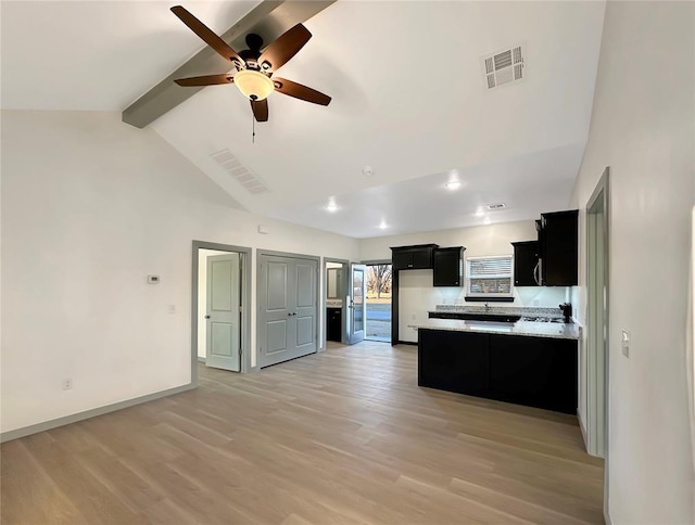 kitchen with light stone counters, light hardwood / wood-style flooring, lofted ceiling with beams, and ceiling fan