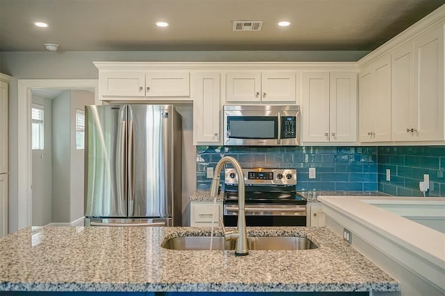 kitchen with white cabinetry, stainless steel appliances, and light stone countertops