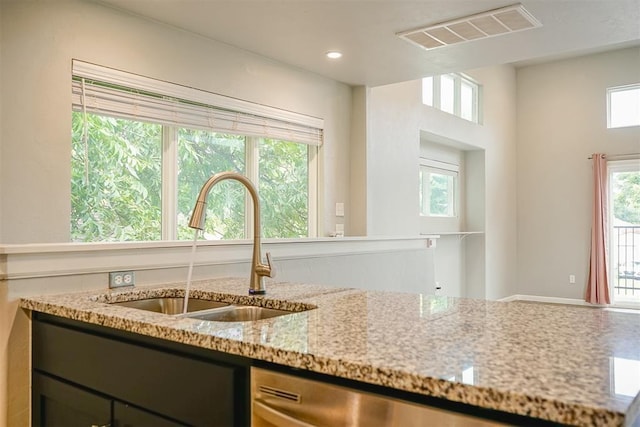 kitchen with plenty of natural light, light stone countertops, and sink