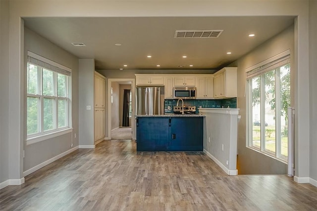 kitchen featuring tasteful backsplash, light hardwood / wood-style flooring, white cabinets, and appliances with stainless steel finishes