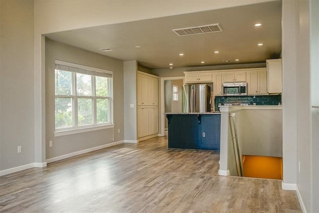 kitchen featuring white cabinetry, stainless steel appliances, tasteful backsplash, light hardwood / wood-style floors, and a kitchen island