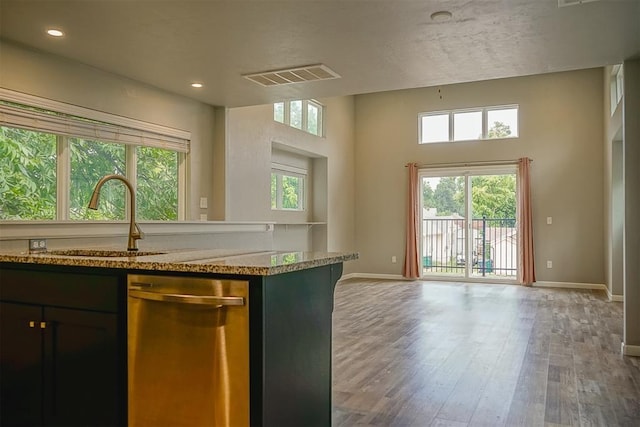 kitchen featuring sink, dark hardwood / wood-style floors, dishwasher, a wealth of natural light, and light stone countertops