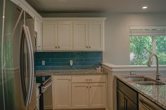 kitchen with light stone counters, sink, white cabinets, and appliances with stainless steel finishes