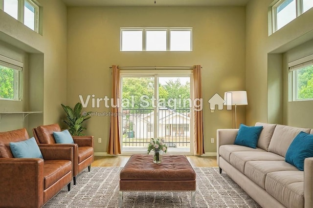 living room featuring a towering ceiling, plenty of natural light, and light hardwood / wood-style floors