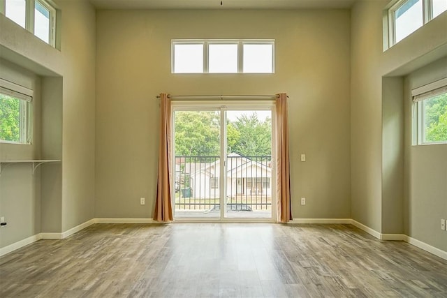 empty room featuring light hardwood / wood-style flooring and a high ceiling