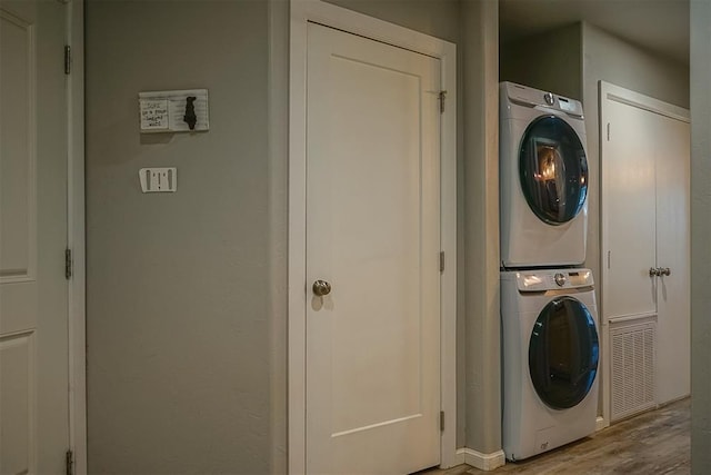 laundry area with stacked washer and clothes dryer and hardwood / wood-style floors