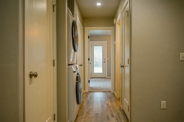 hall with light wood-type flooring and stacked washer / dryer