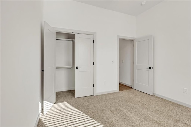 unfurnished bedroom with light colored carpet and a closet