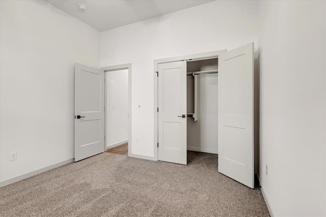 unfurnished bedroom with light colored carpet and a closet