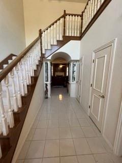 staircase featuring tile patterned flooring and a high ceiling