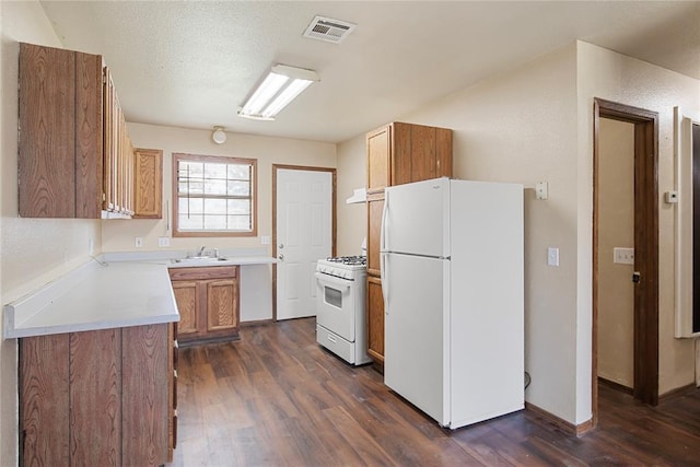 kitchen with dark hardwood / wood-style floors, sink, a textured ceiling, and white appliances