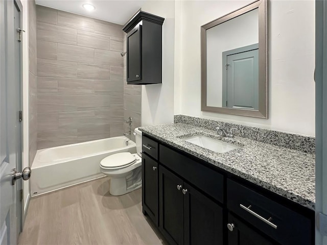 full bathroom with vanity, tiled shower / bath, wood-type flooring, and toilet