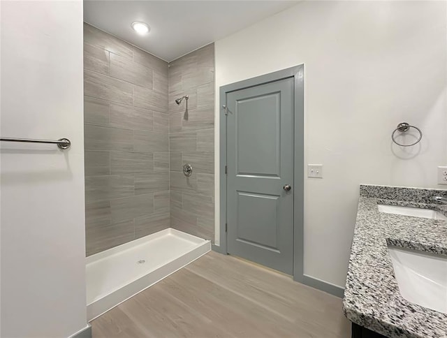 bathroom featuring wood-type flooring, vanity, and a tile shower