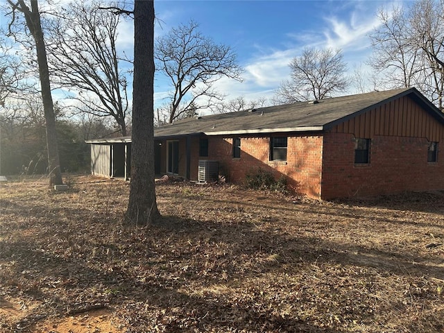 view of side of property featuring central AC unit and brick siding