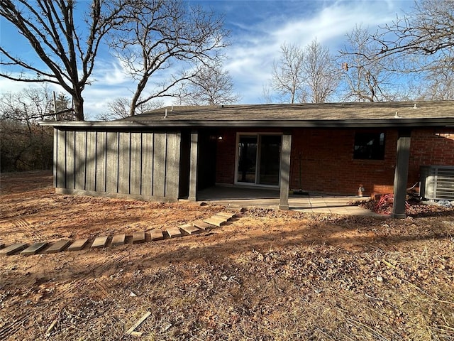 back of house featuring cooling unit, brick siding, and a patio