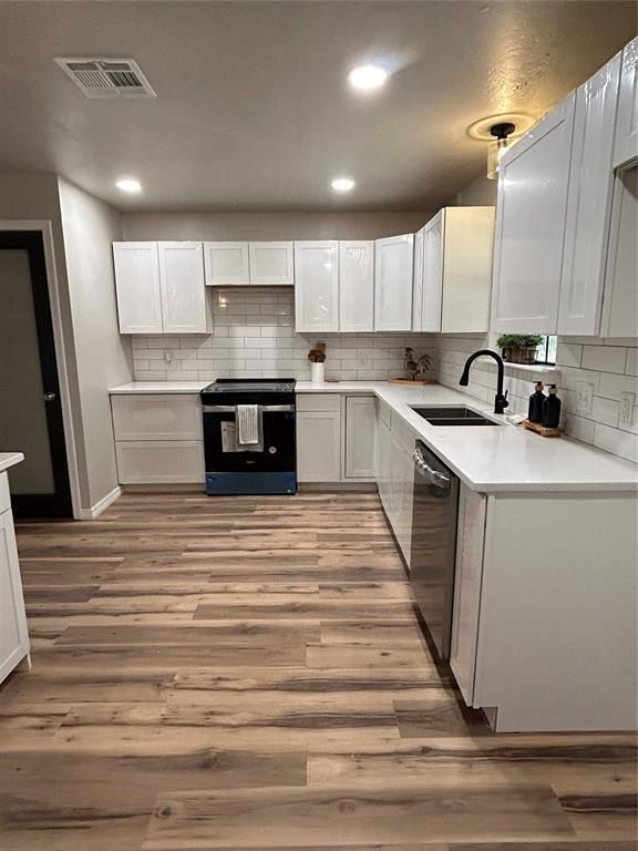 kitchen with range with electric cooktop, white cabinetry, and a sink