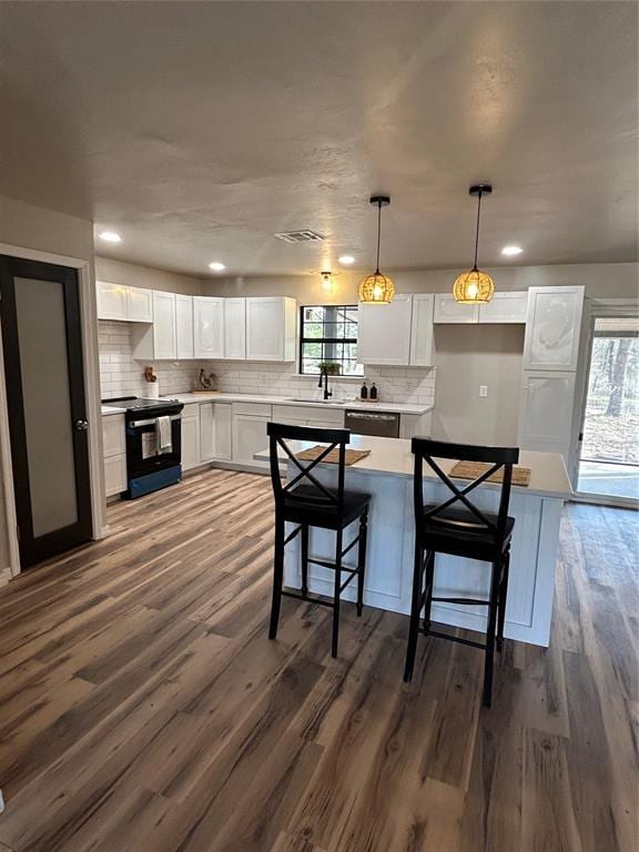 kitchen with electric stove, light countertops, decorative light fixtures, and white cabinets