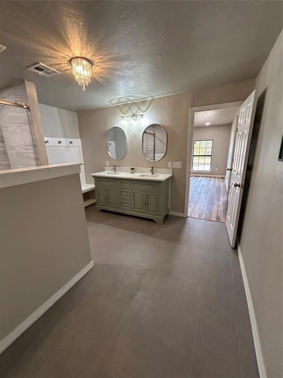 bathroom with double vanity, visible vents, an inviting chandelier, a sink, and baseboards