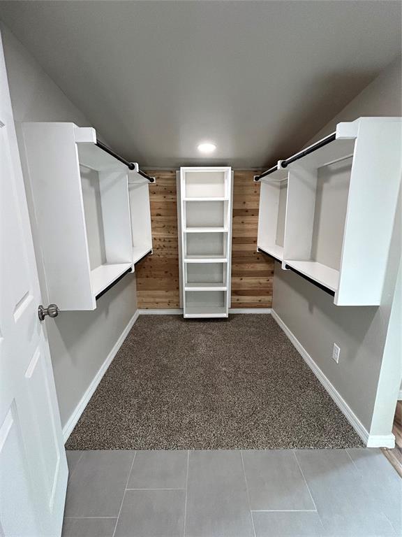 spacious closet with light colored carpet and light tile patterned flooring