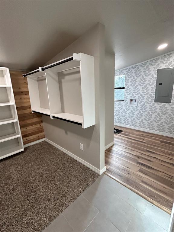 spacious closet with lofted ceiling, tile patterned flooring, and electric panel