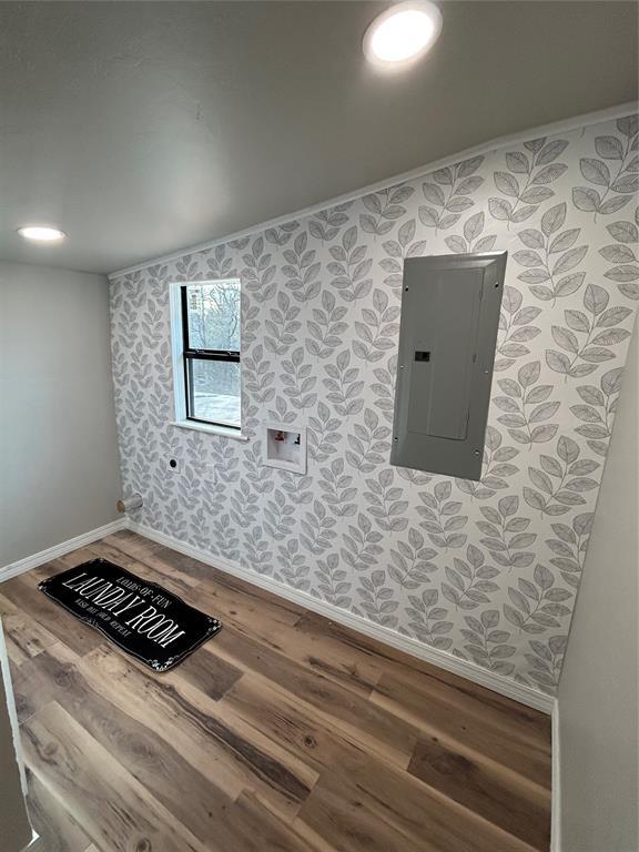 interior space with wallpapered walls, electric panel, baseboards, and wood finished floors