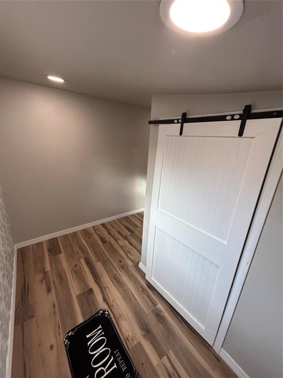 interior space with a barn door, baseboards, and dark wood-type flooring