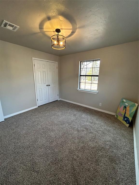 unfurnished bedroom featuring dark colored carpet, a closet, visible vents, and baseboards