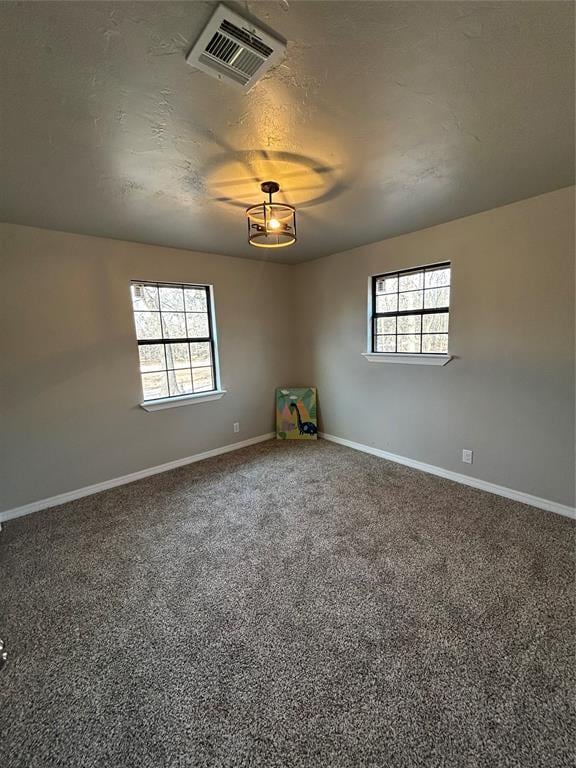 carpeted spare room with plenty of natural light, visible vents, and baseboards