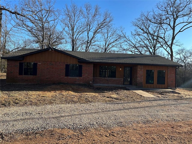 ranch-style house with dirt driveway, brick siding, and board and batten siding