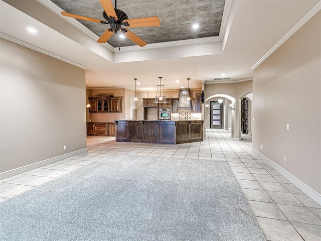 unfurnished living room featuring light tile patterned flooring, ceiling fan, ornamental molding, and a tray ceiling