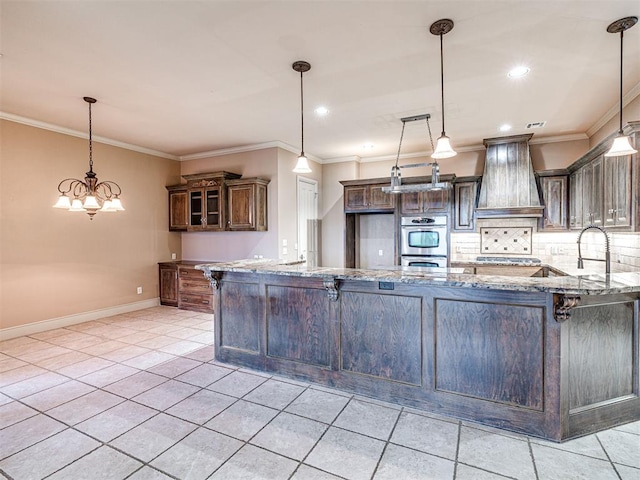 kitchen with appliances with stainless steel finishes, decorative light fixtures, kitchen peninsula, light stone countertops, and custom range hood