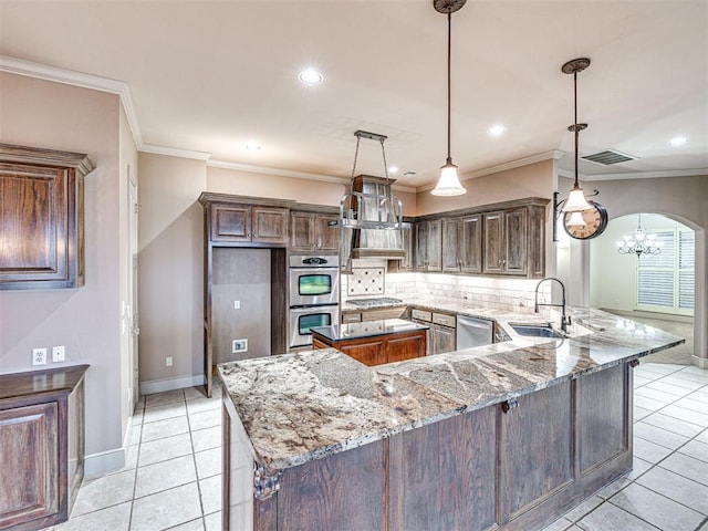 kitchen with sink, light stone counters, appliances with stainless steel finishes, kitchen peninsula, and pendant lighting