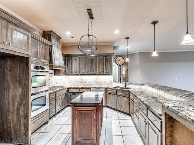 kitchen featuring hanging light fixtures, dark brown cabinets, dark stone counters, and a kitchen island