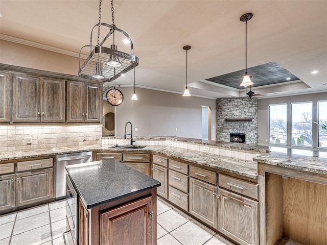 kitchen with sink, stainless steel dishwasher, a raised ceiling, pendant lighting, and decorative backsplash