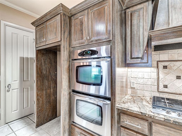 kitchen with light tile patterned flooring, tasteful backsplash, ornamental molding, double oven, and light stone countertops