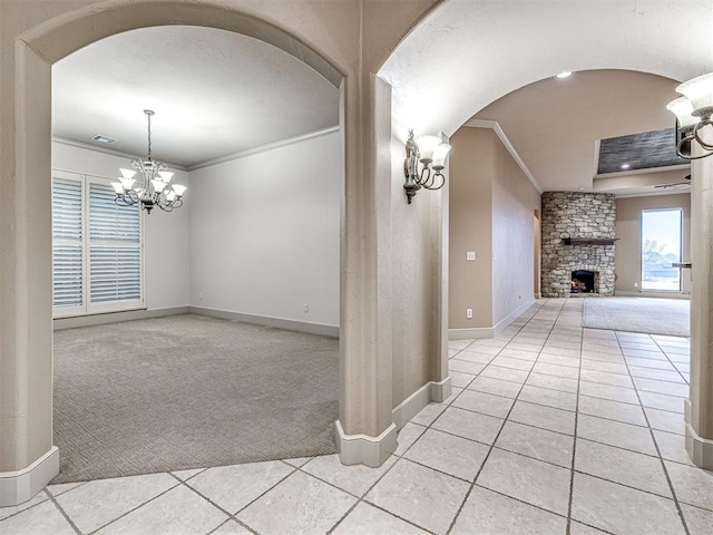 carpeted empty room with a notable chandelier, a fireplace, and ornamental molding