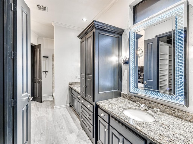 bathroom with hardwood / wood-style flooring, ornamental molding, and vanity