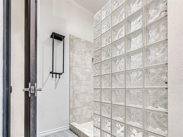 bathroom with crown molding and tiled shower