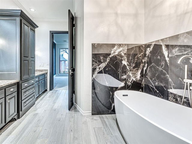 bathroom with vanity, hardwood / wood-style floors, crown molding, and a tub