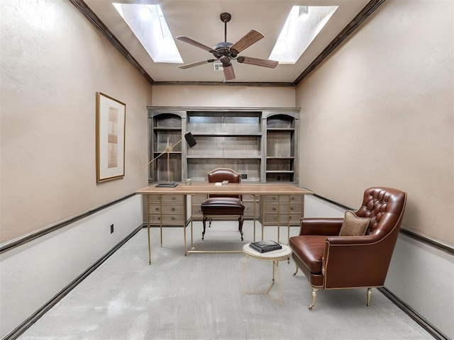 carpeted home office featuring ornamental molding, ceiling fan, and a skylight