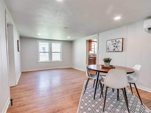 dining area with a wall mounted AC and light hardwood / wood-style floors