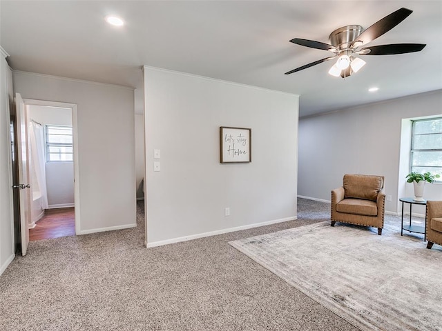 living area with crown molding, ceiling fan, and carpet