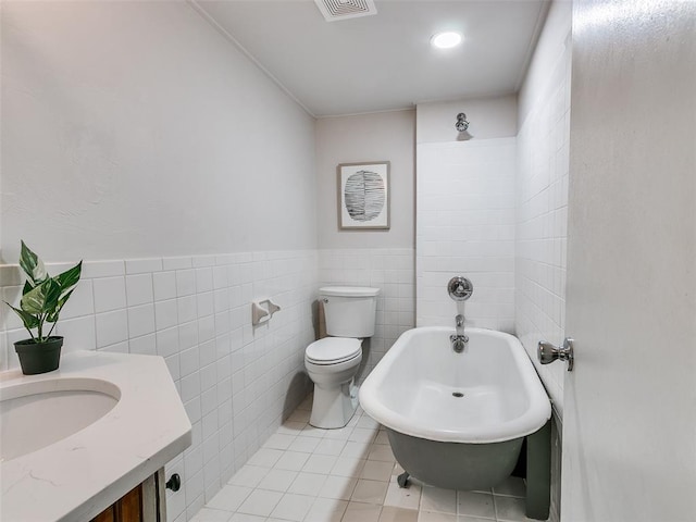 bathroom with toilet, tile patterned flooring, and tile walls